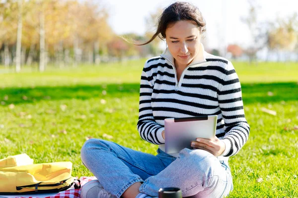 Νεαρή Γυναίκα Που Χρησιμοποιεί Tablet Κάθεται Στο Πάρκο — Φωτογραφία Αρχείου