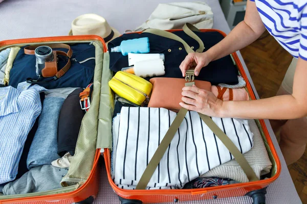 stock image Young woman packing suitcase for summer travel, including sunscreen and camera