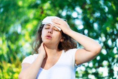 Young woman having hot flash and sweating in a warm summer day. Woman drying with paper napkin in too hot weather clipart