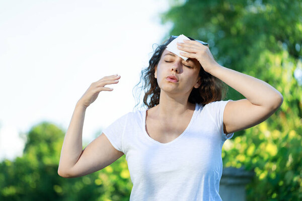 Молодая женщина горячая вспышка и потливость в теплый летний день. Женщина сушит бумажную салфетку в слишком жаркую погоду