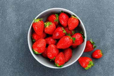 Mermer arka planda bir kasede lezzetli taze çilekler.