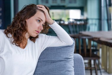 Depresyondaki genç bir kadın evde yalnız başına kendini kötü hissediyor. Oturma odasında kanepede oturuyor ve düşünüyor.