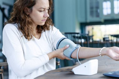 Genç serbest çalışan kadın masasında kan basıncını ölçüyor.