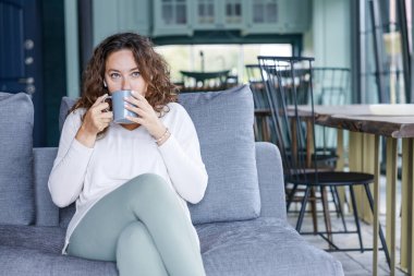 Genç bayan kanepede oturup kahve içiyor. Boş zaman aktivitesi, insanların yaşam tarzı kavramı