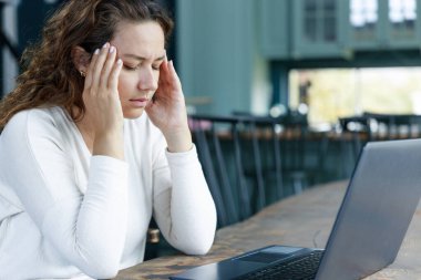 Ofiste çalışan genç bir kadın baş ağrısı çekiyor.