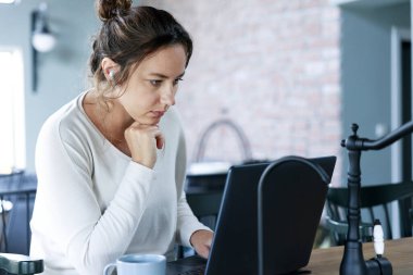 Dizüstü bilgisayara bakan serbest çalışan genç bir kadın.