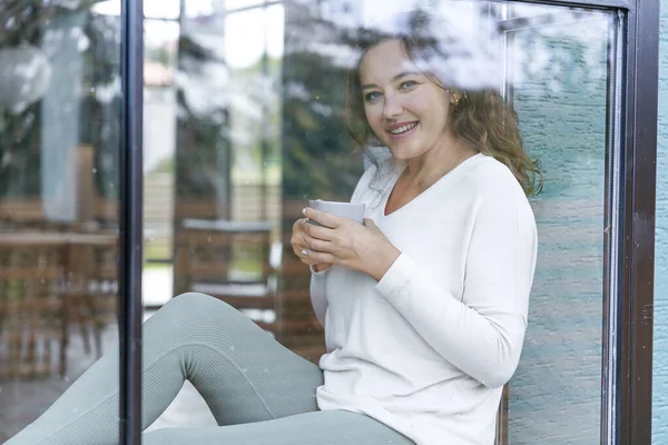 Mid Vuxen Kvinna Dricker Kaffe Och Tittar Genom Fönstret — Stockfoto