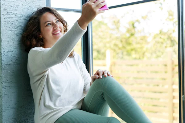 Piękna Kobieta Luźnych Ubraniach Robi Selfie Pomocą Smartfona Uśmiecha Się — Zdjęcie stockowe