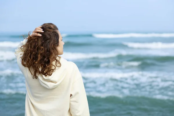 一个卷发的年轻女子独自远眺大海 后视镜 图库照片