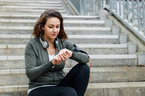 Fit female runner using smart watch to monitor her performance. Sportswoman checking her workout progress. Using smart watch after workout outdoor in the city