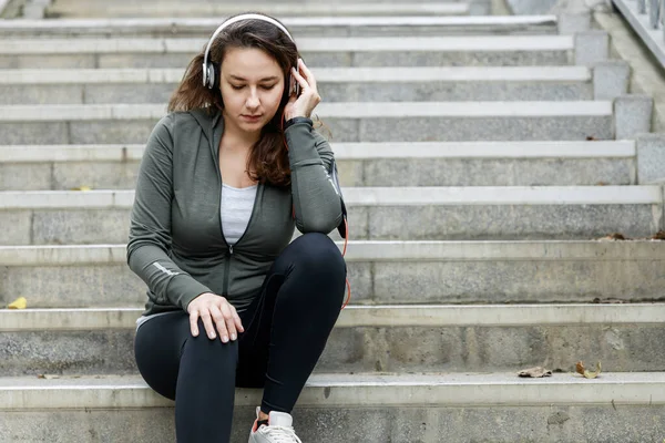 Молодая Спортивная Женщина Слушает Музыку Белых Наушниках Сидя Лестнице Отдохнуть — стоковое фото