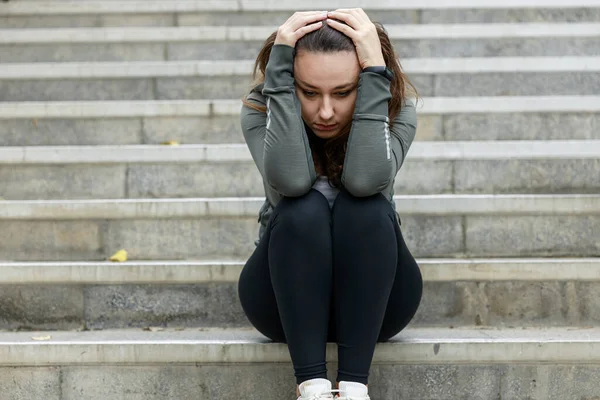 Disappointed and sad woman sitting on stairs. She sits alone and thinks on a sad and depressed on the stairs