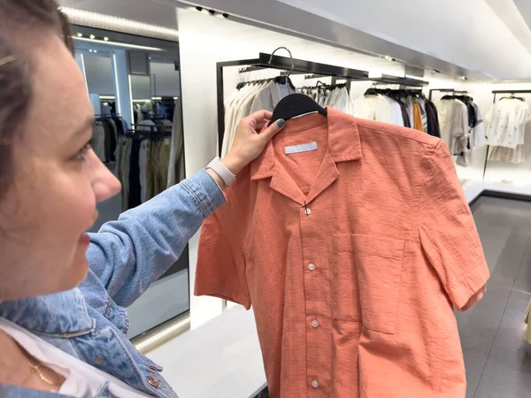 在商场或服装店里 年轻女人选择衣服 手里拿着衣架看衬衫 免版税图库图片