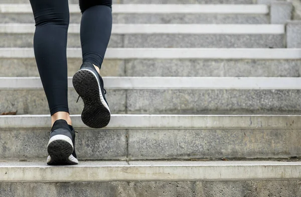 在楼梯上对一名女运动员进行高强度训练 城市里无法辨认的女运动员慢跑 免版税图库图片