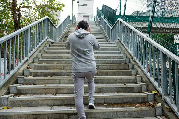 ヘッドフォンを持った若者は2階に向かって歩いている スポーツ フィットネス 健康的なライフスタイルコンセプト ロイヤリティフリーのストック写真