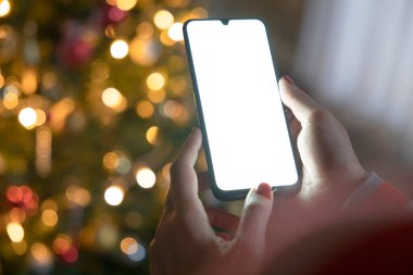 Cropped of woman's hands holding smartphone at Christmas time. Digital mobile phone with copy space area clipart