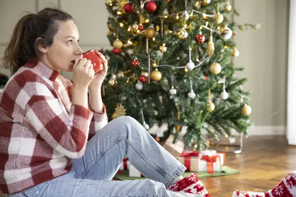 在圣诞节前喝咖啡的年轻女人 免版税图库图片