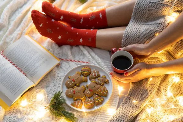 若い女性はベッドでかわいいジンジャーブレッドクッキーでコーヒーを飲みました クリスマス リラクゼーションコンセプト ストック画像