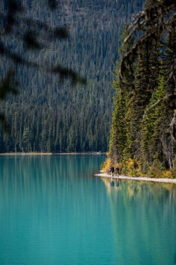 Sahilde zümrüt göl etrafında yürüyüş yapan bir grup insan.
