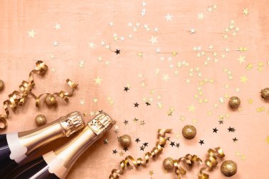 İki şampanya şişesi ve şeftali rengi arka planda altın yıldız konfetisi. Noel, Yeni Yıl, Purim kutlama konsepti