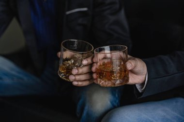 Viski kadehi tutan ciddi işadamlarının yakın çekimi yürütme ayrıcalığı kavramını gösteriyor. Yumuşak odaklanma. Resmi olarak iki adamın yakın çekim görüntüsü viski bardakları takıyor.