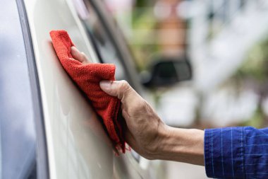 Arabayı kontrol eden genç adam arabayı temizliyor. Genç Asyalı adam elinde mikrofiber tutarak arabayı cilalıyor. Araç teftişi ve bakım hizmetleri.