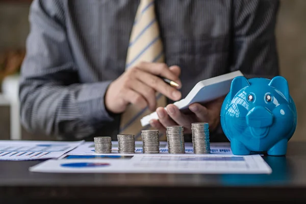 貯金の概念と並んでコインの山で財務を計算するビジネスマン — ストック写真