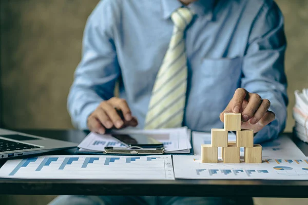 businessman laying empty wooden blocks business management concept planning and strategy Setting and achieving goals with financial graphs on the table Risk assessment. investment