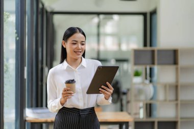 Kameraya bakan mutlu Asyalı kadın satıcı gülümseyen kadın yönetici ofiste dijital tablet bulunduran profesyonel iş hizmetleri sunuyor.