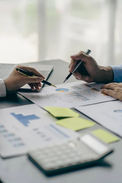 close-up group of business people with financial graphs and money pens An accountant holding a pen pointing to a chart of documents for a team meeting in the office Finance and Accounting Concepts vertical picture