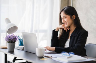 Ofiste finans ve iş bilgileri üzerinde çalışan Asyalı iş kadını. Gençler kağıt grafiklerden elde edilen verileri kullanarak planları analiz ediyorlar..