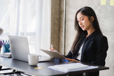 Ofiste finans ve iş bilgileri üzerinde çalışan Asyalı iş kadını. Gençler kağıt grafiklerden elde edilen verileri kullanarak planları analiz ediyorlar..