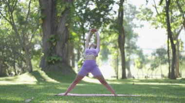 Bahçede yoga yapan Asyalı bir kadın yaşam tarzı, spor ve sağlık kavramını geliştirmek için. Kadın dışarıda yoga yapıyor.