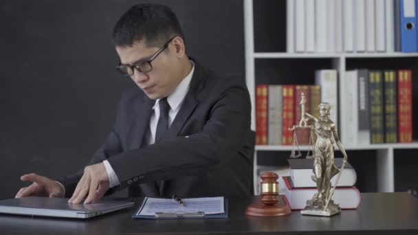 Asyalı Erkek Avukat Çekiç Bilgisayarıyla Çalışıyor Hukuk Bürosunda Adalet Tanrıçası — Stok video