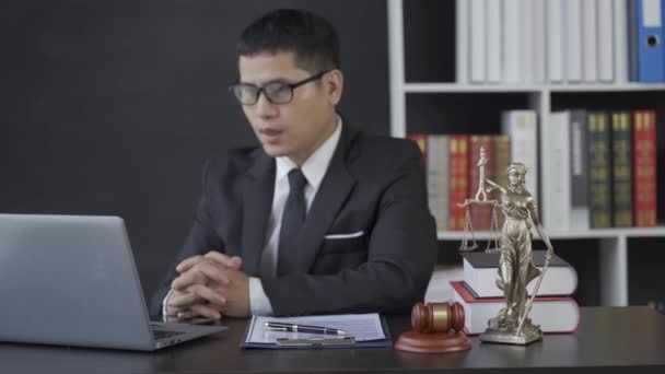 ハンマーノートパソコンで働くアジアの男性弁護士法律事務所で正義の女神 オンラインコンサルティングの概念 — ストック動画