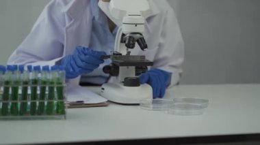 Laboratuvarda kimya deneyleri yapan kadın bir bilim adamı. Şapkalı ve maskeli güzel bir kadın doktor, kırmızı ve yeşil sıvı içeren cam bir şişeye test tüpü yerleştiriyor..