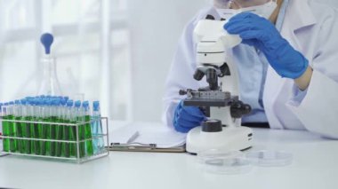 Laboratuvarda kimya deneyleri yapan kadın bir bilim adamı. Şapkalı ve maskeli güzel bir kadın doktor, kırmızı ve yeşil sıvı içeren cam bir şişeye test tüpü yerleştiriyor..