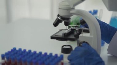 Laboratuvarda kimya deneyleri yapan kadın bir bilim adamı. Şapkalı ve maskeli güzel bir kadın doktor, kırmızı ve yeşil sıvı içeren cam bir şişeye test tüpü yerleştiriyor..