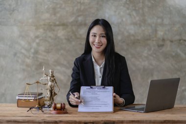 Asyalı avukat adalet tanrısının terazisiyle çalışır. Masasında güzel ve profesyonel bir Asyalı kadın avukat ya da hukuk danışmanı oturuyor. Adalet ve hukuk kavramının terazisini elinde tut