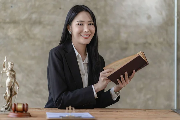 Asian lawyer Work with the scales of the god of justice. A beautiful and professional Asian woman lawyer or legal advisor sits at her desk. hold the scales of justice legal concept