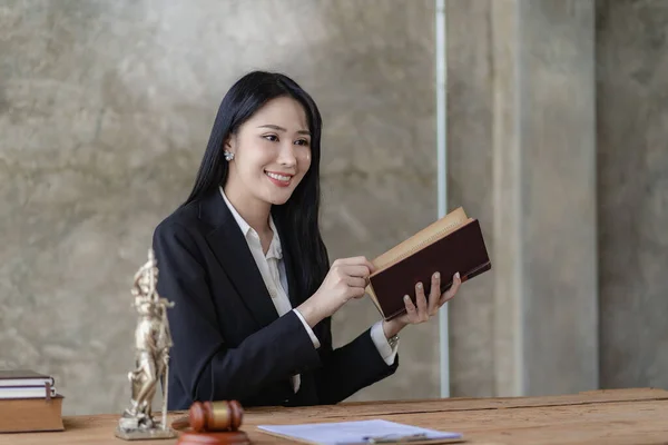 Asian lawyer Work with the scales of the god of justice. A beautiful and professional Asian woman lawyer or legal advisor sits at her desk. hold the scales of justice legal concept