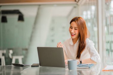 Genç Asyalı iş kadını online finans konsepti dizüstü bilgisayarının önünde başarılı iş yapma konusunda heyecanlı.