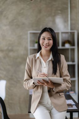 Modern ofiste dizüstü bilgisayarı olan mutlu gülümseyen Asyalı iş kadını, finansal muhasebe kavramı. dikey resim