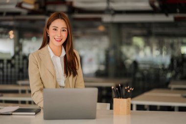 Modern ofiste dizüstü bilgisayarı olan mutlu gülümseyen Asyalı iş kadını online muhasebe kavramını finanse ediyor.