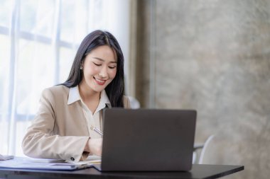 Finans ve hesap makinesinde çalışan Asyalı iş kadını ofis teknoloji piyasası ve finansal kavramlarda kağıt belgelerle dizüstü bilgisayarla çalışıyor.