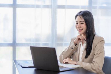 Finans ve hesap makinesinde çalışan Asyalı iş kadını ofis teknoloji piyasası ve finansal kavramlarda kağıt belgelerle dizüstü bilgisayarla çalışıyor.