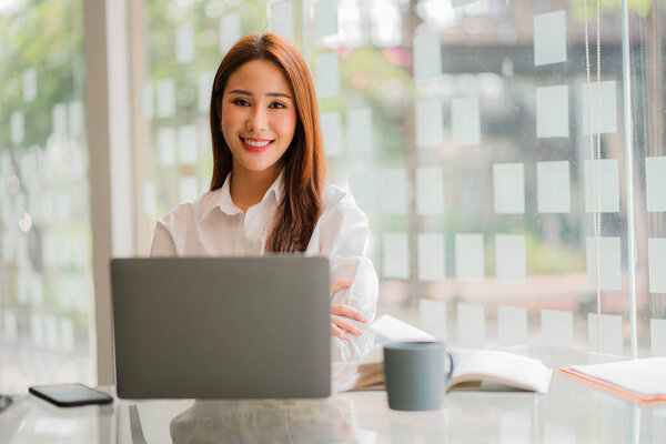 Happy smiling Asian businesswoman with laptop computer in modern office finance online accounting concept.