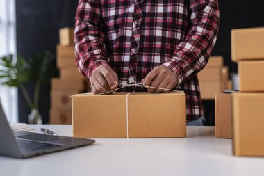 Çevrimiçi iş fikri, genç girişimci, evde dizüstü bilgisayarla ve akıllı telefonla çalışıyor, siparişleri alıyor ve paketleri teslim ediyor..
