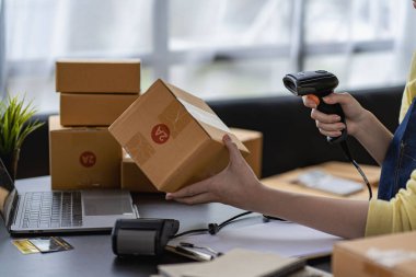 Çevrimiçi iş fikri, genç girişimci, evde dizüstü bilgisayarla ve akıllı telefonla çalışıyor, siparişleri alıyor ve paketleri teslim ediyor..