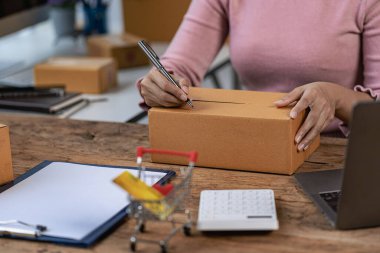 Çevrimiçi iş fikri, genç girişimci, evde dizüstü bilgisayarla ve akıllı telefonla çalışıyor, siparişleri alıyor ve paketleri teslim ediyor..